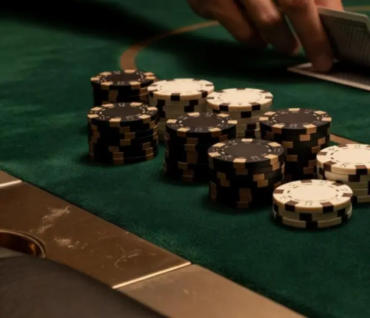 Close-up of a professional poker table with green felt, chips and cupholders.
